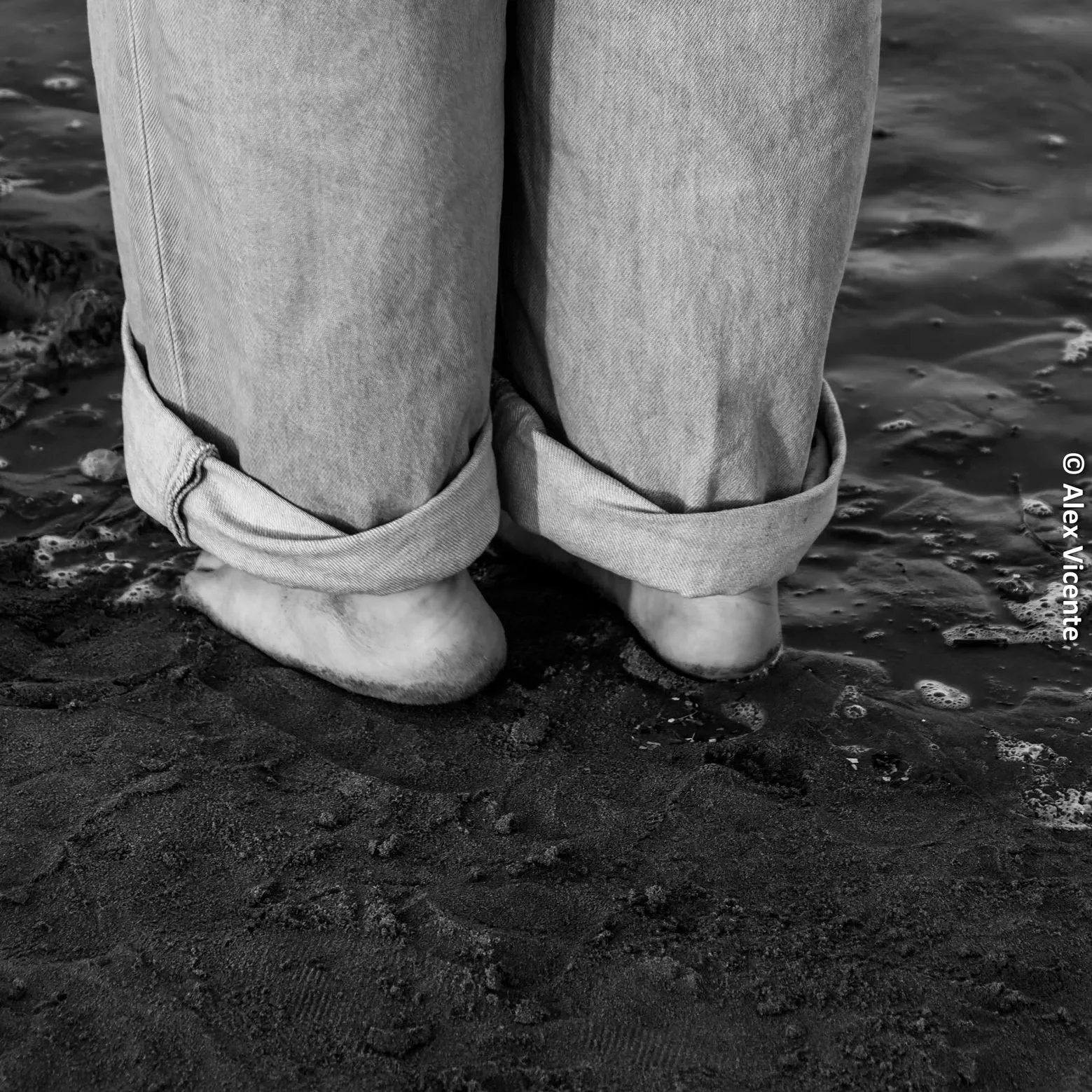 Bare feet on wet sand beside the sea.