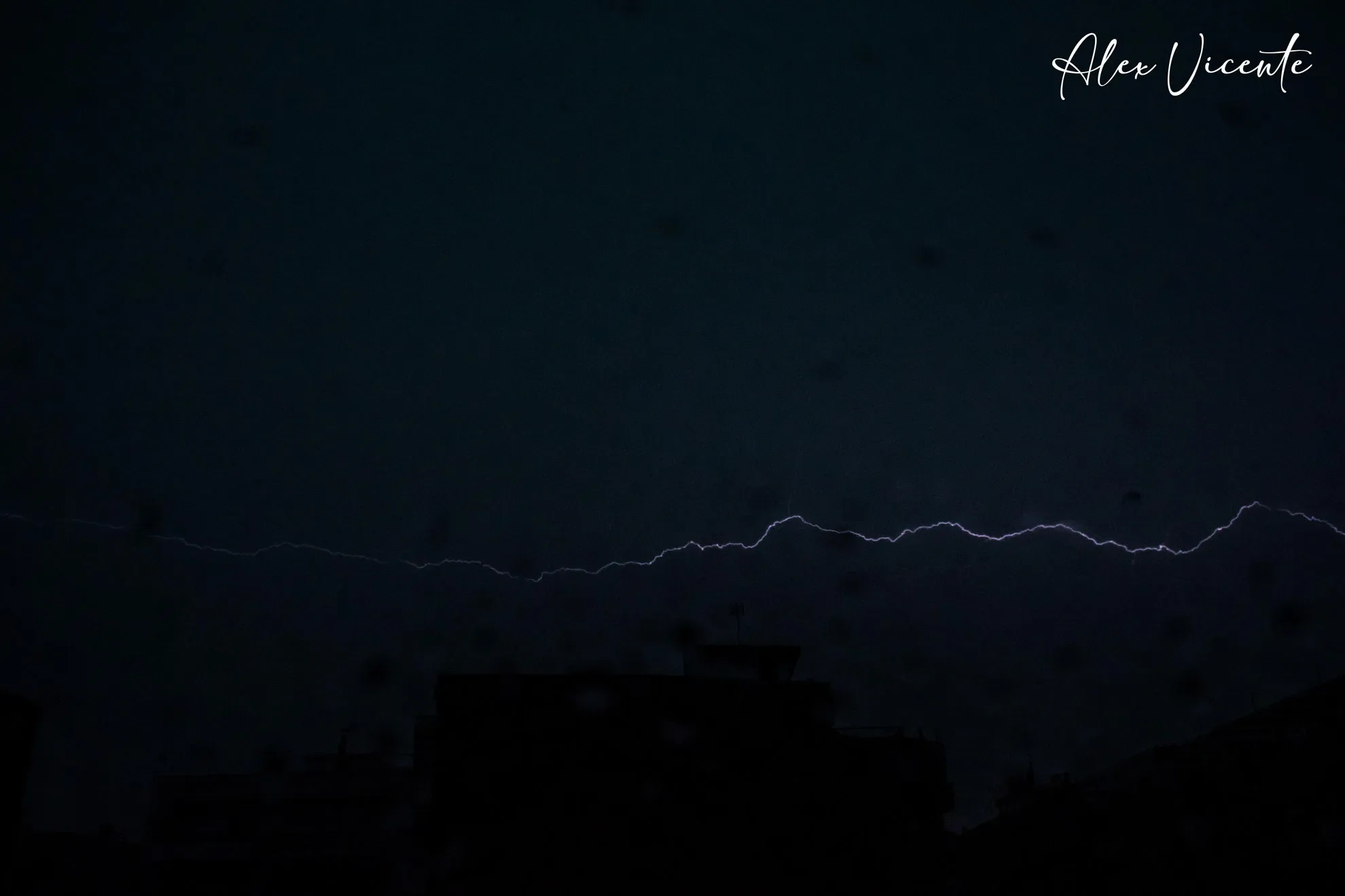 Lightning over city silhouettes at night.